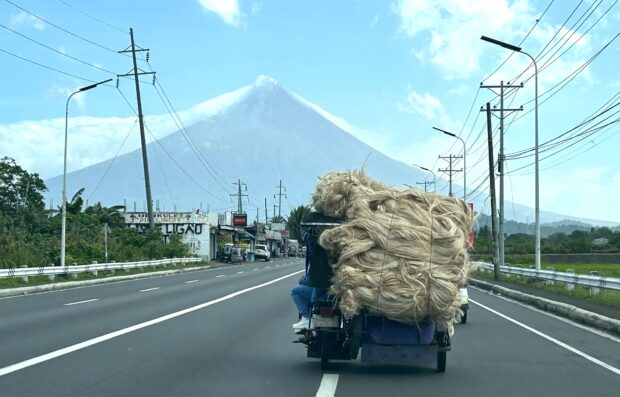 PHOTO: A tricycle loaded with abaca fiber traverses the national highway in Ligao City, Albay, amid a scenic backdrop provided by Mt. Mayon. The volcano, with its perfect cone visible during cloudless days, and abaca are among the most recognizable landmarks and products of the Bicol region. STORY: Mayon quiets down; alert now at level 1