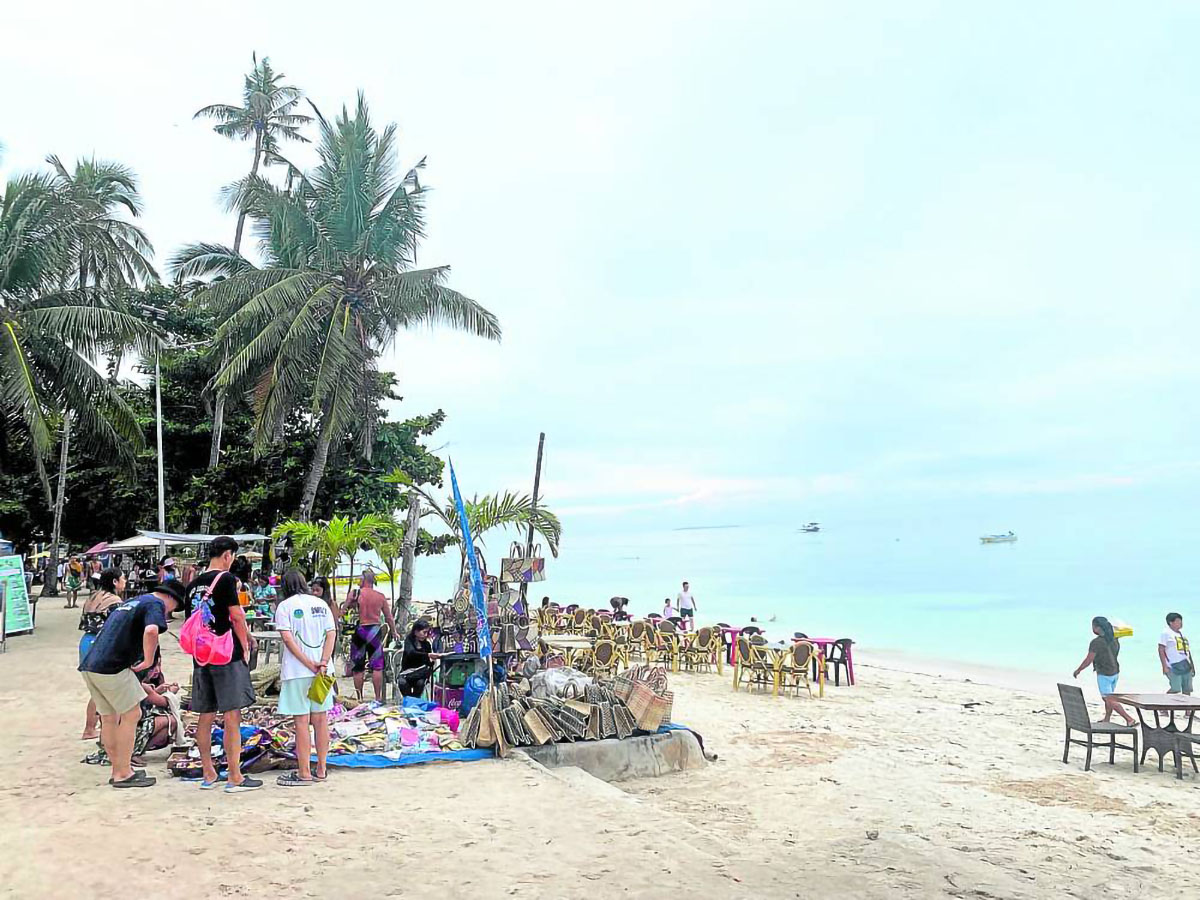 Vendors offer souvenir itemsto tourists on Alona Beach in this August 2022 photo. Bars, restaurants and hotels along the beach also set up dining areas on the beach so visitors can enjoy the view. 