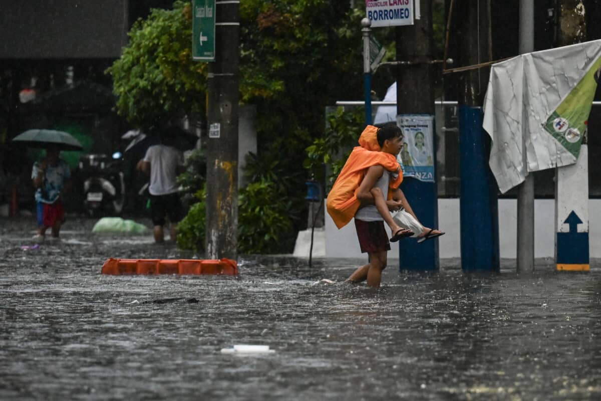 A man piggybacks a person along a flooded street in Manila on July 24, 2024 amid heavy rains brought by Typhoon Gaemi.