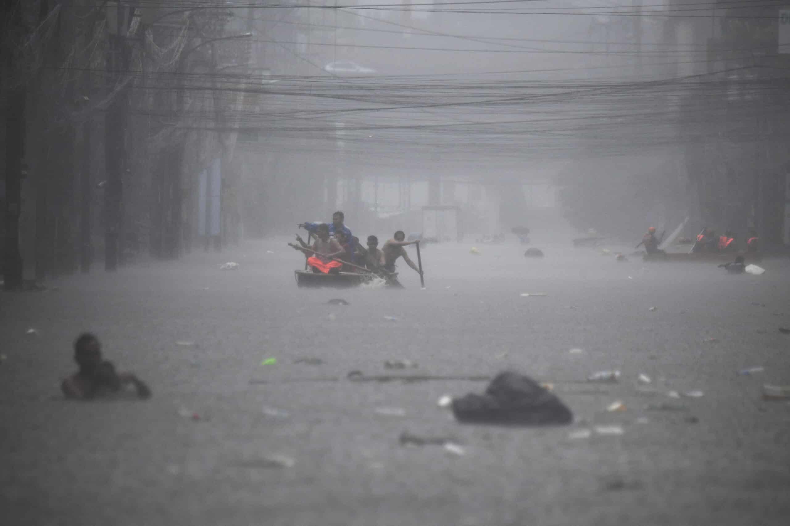 Rescuers paddle their boats along a flooded street in Manila on July 24, 2024 amid heavy rains brought by Typhoon Gaemi.