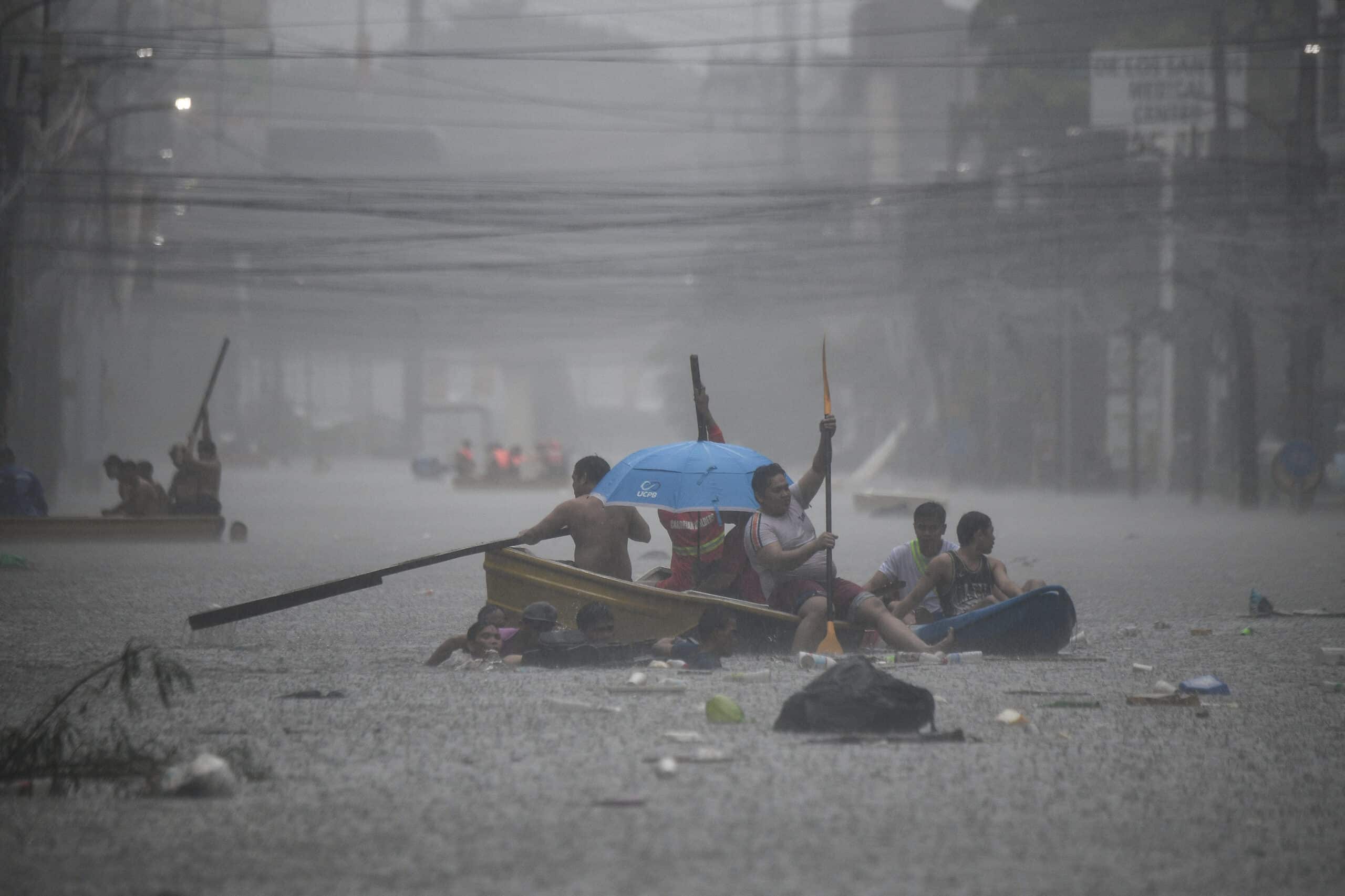 Rescuers paddle their boats along a flooded street in Manila on July 24, 2024 amid heavy rains brought by Typhoon Gaemi.
