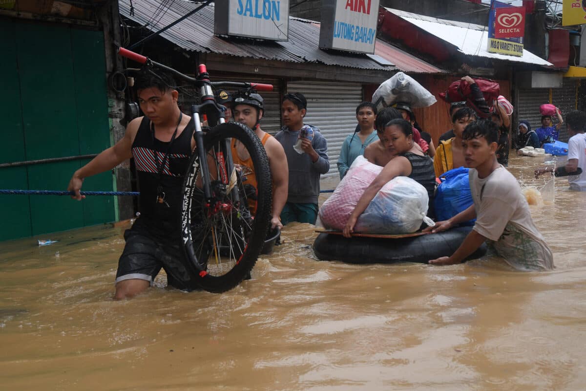 PHOTO: A resident with their belongings ride on an improvised inflatable buoy made from the interior of a tire along with other residents evacuate from their flooded homes in Barangay Tumana, Marikina City, east of Manila on July 24, 2024, amid heavy rains brought about by Typhoon Carina (international name: Gaemi). STORY: Carina evacuees get aid: 3,000 in Navotas, 10,000 in Marikina