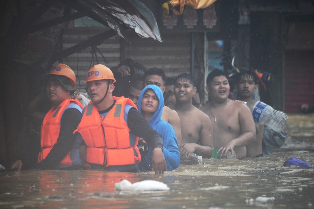 Rescuers (front L) guide residents with their belongings as they evacuate from their flooded homes in Tumana village, Marikina City, east of Manila on July 24, 2024, amid heavy rains brought about by Typhoon Gaemi. Relentless rain drenched the northern Philippines on July 24, triggering flooding in Manila and landslides in mountainous regions as Typhoon Gaemi intensified the seasonal monsoon. (Photo by Ted ALJIBE / AFP)
