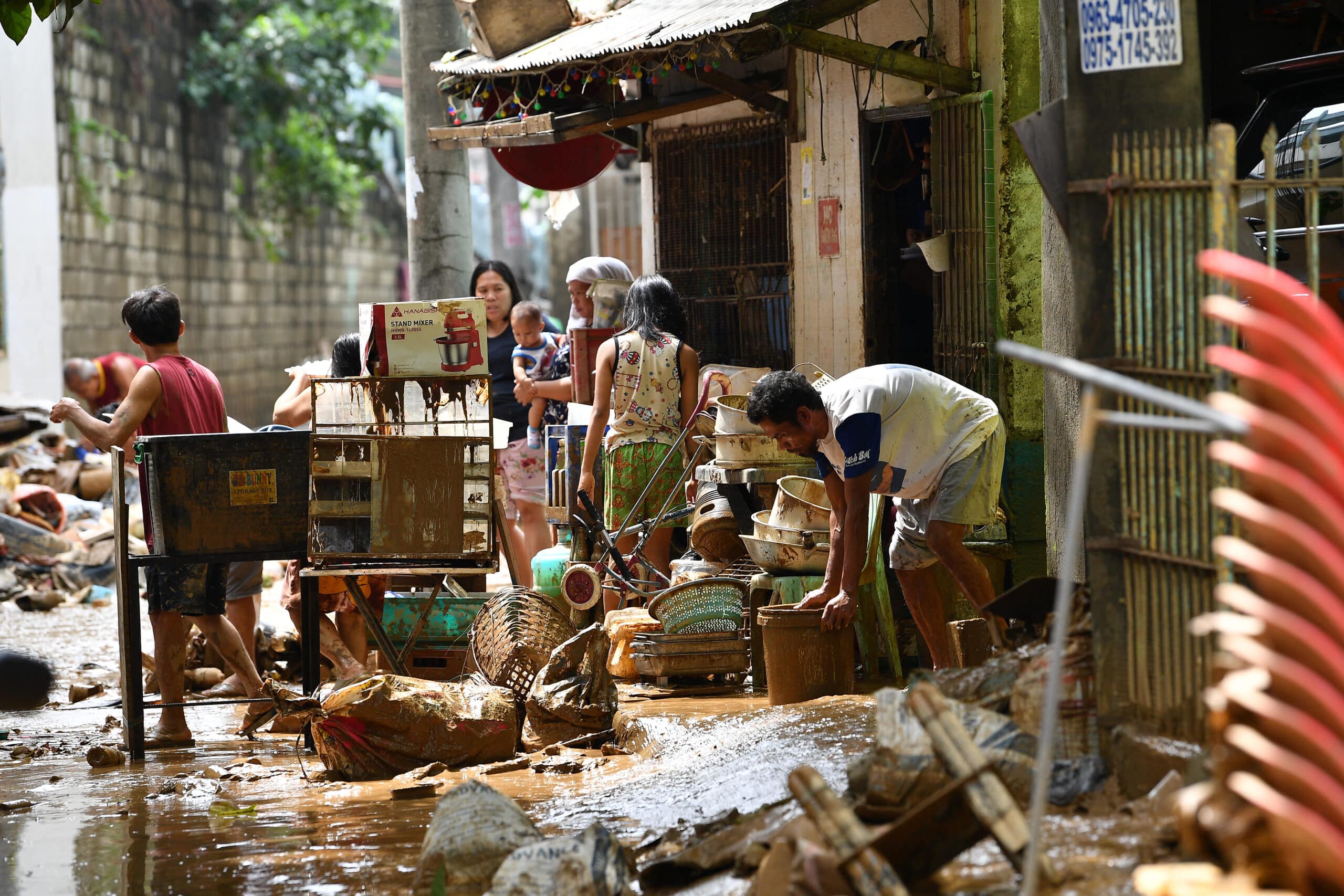 Residents check their belongings at a village in Manila on July 25, 2024, a day after heavy rains fuelled by Typhoon Gaemi and the seasonal monsoon lashed Manila and surrounding regions in recent days.