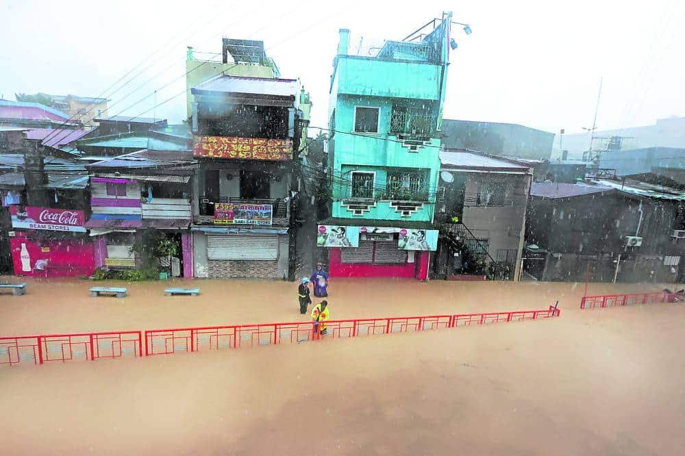 Residents on a flooded street in Marikina City evacuate to higher ground after authorities raised the third alarm for the Marikina River when it breached the 18-meter mark and continued to rise on Wednesday morning.