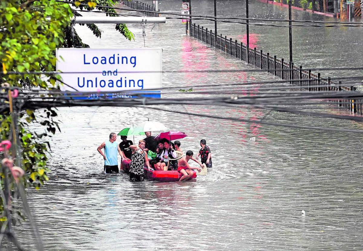 To avoid getting drenched, people cram themselves on a makeshift banca,as it is pushed along the perennially flooded España Boulevard in Manila, on Wednesday, following heavy rains that prompted the declaration of a state of calamity in Metro Manila.