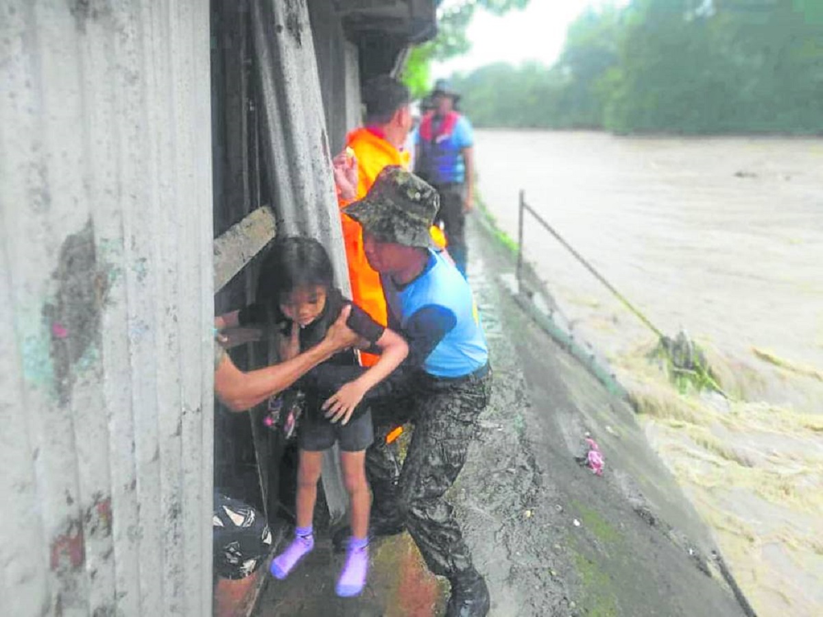 Policemen help evacuate members of a familyliving along a river in San Jose del Monte City in Bulacan on Wednesday as Supertyphoon “Carina” batters Luzon. 