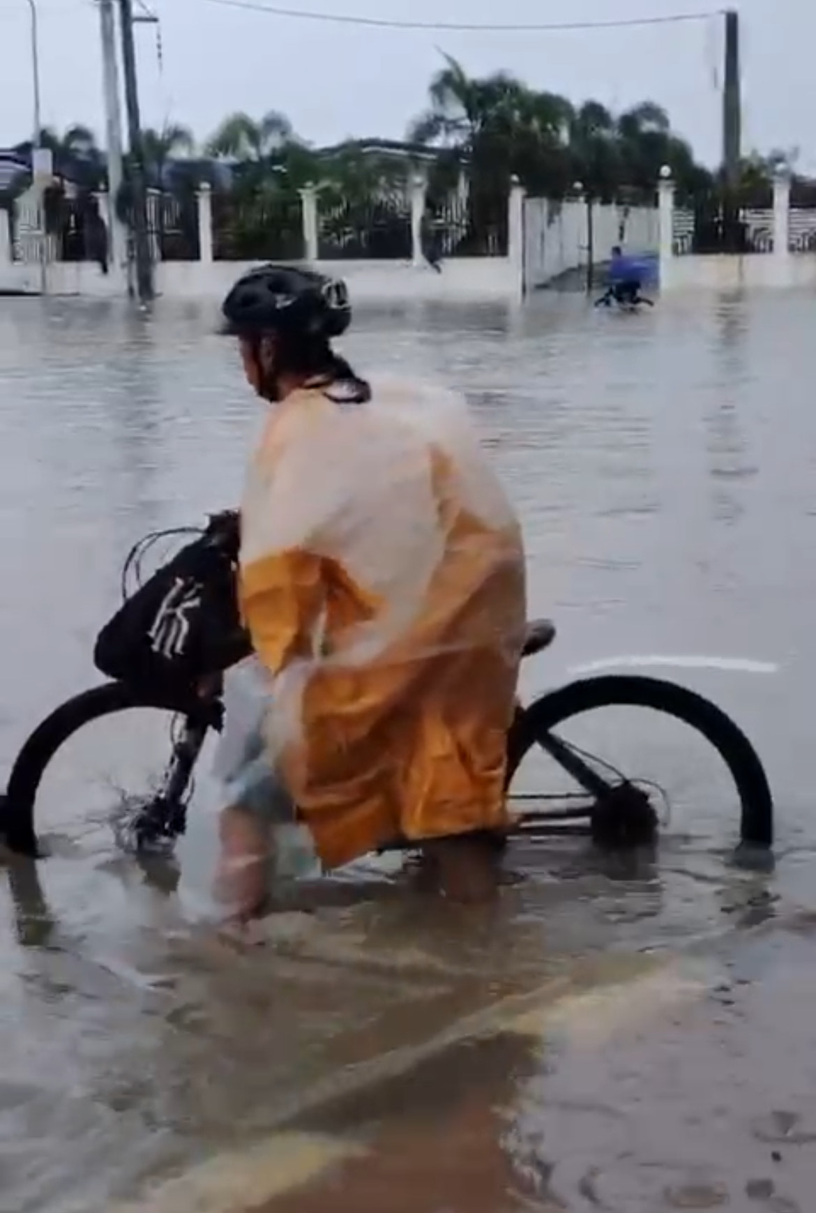 A cyclist passes through the gutter-deep floods. 