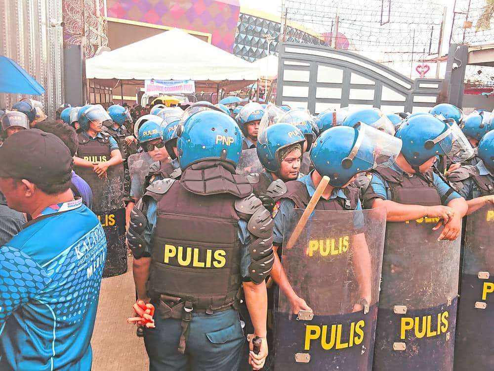 FIFTH TRY Some of the 2,000 police officers mobilized on August 24, 2024 to again serve an arrest warrant on televangelist Apollo Quiboloy, assembled outside the ingdom of Jesus Christ compound in Davao City.