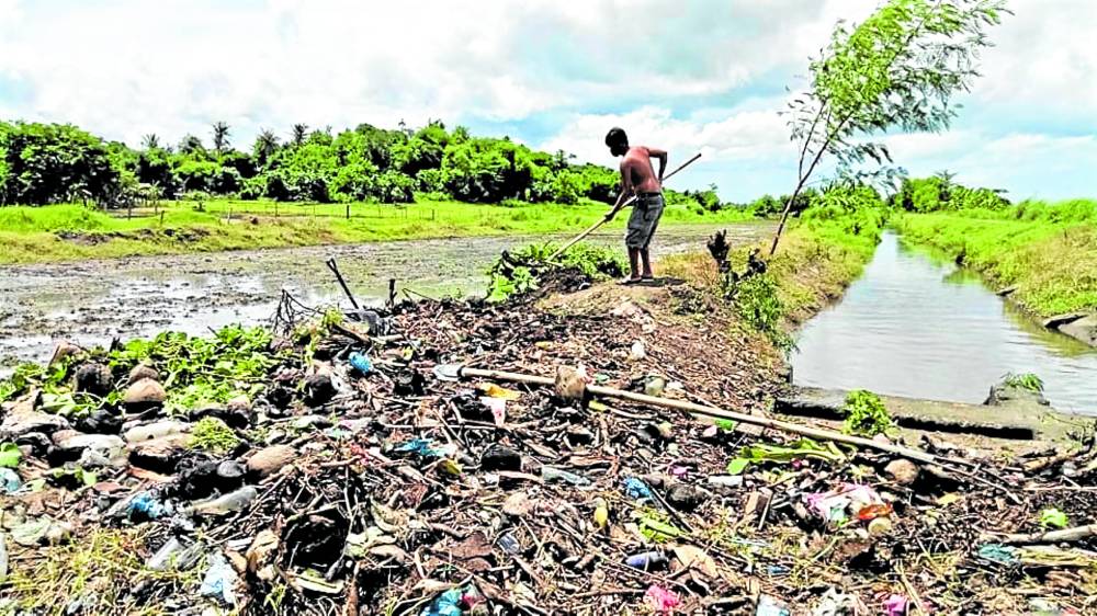 A farmer in Magarao, Camarines Sur province, clears assorted debris along irrigation canals after Tropical Storm “Enteng” (international name: Yagi) hit parts of Bicol and EasternVisayas regions on Sunday. The National Irrigation Administration (NIA) in Bicol has started cleanup activities to prevent clogging and ensure water flowin its canals. 