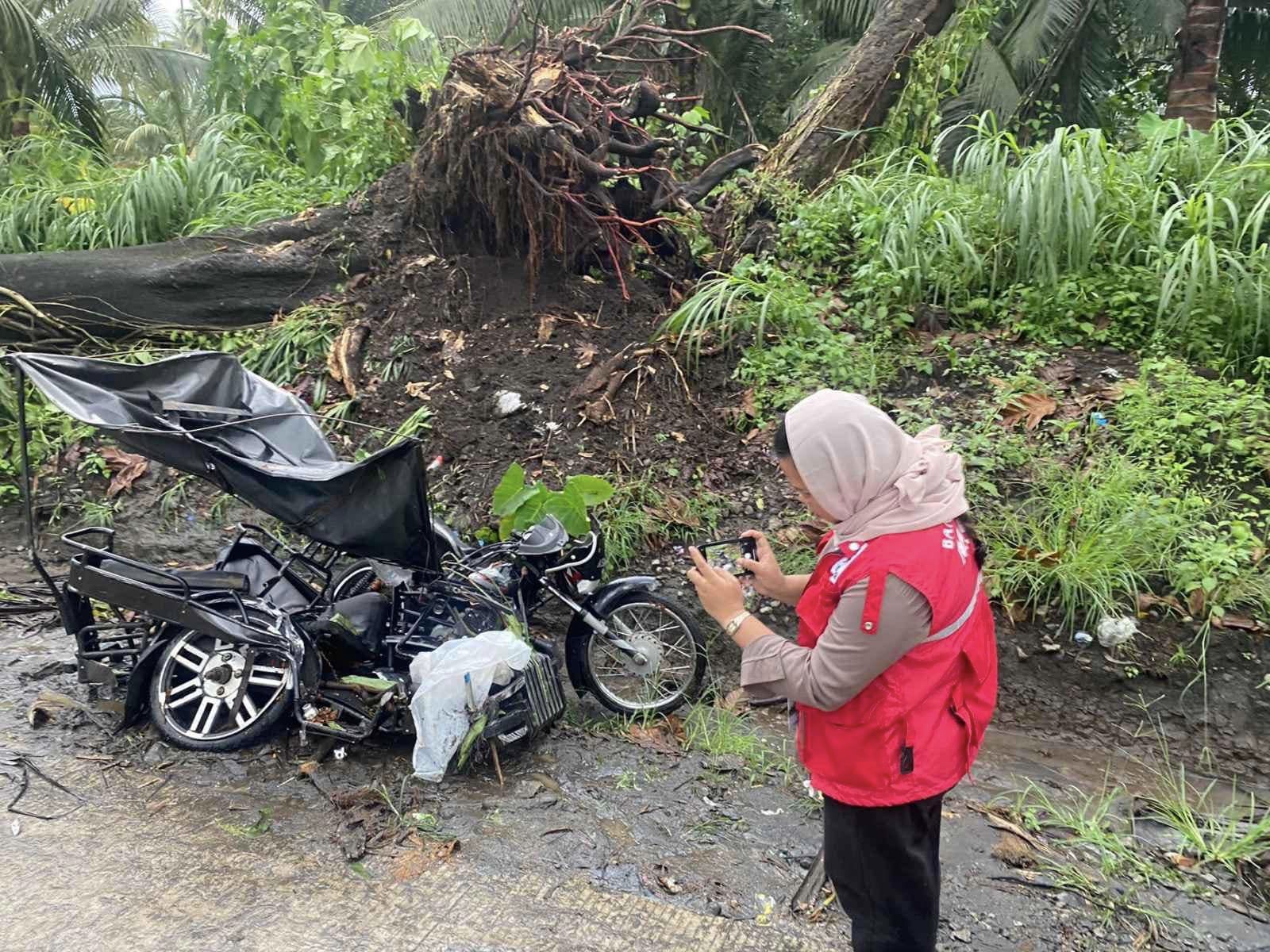 A social worker documents what is left of a tricycle boarded by Arabic school students after it was hit by a fallen tree in Malabang, Lanao del Sur on Friday afternoon. 