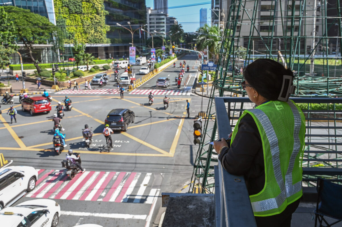 This photo taken on August 22, 2024 shows a traffic surveyor manually counting passing vehicles from a footbridge in Pasig City, Metro Manila. - Rain or shine, through floods and car exhaust pollution, some 34 traffic surveyors employed by the city government are deployed to at least 16 major roads in the Philippine capital - their eyes jumping from one car to the next, fingers clicking manual tally counters as they log each passing vehicle. Their tallies end up with the traffic engineers of the Metropolitan Manila Development Authority (MMDA), who design and propose inexpensive traffic solutions. (Photo by Jam Sta Rosa / AFP) 