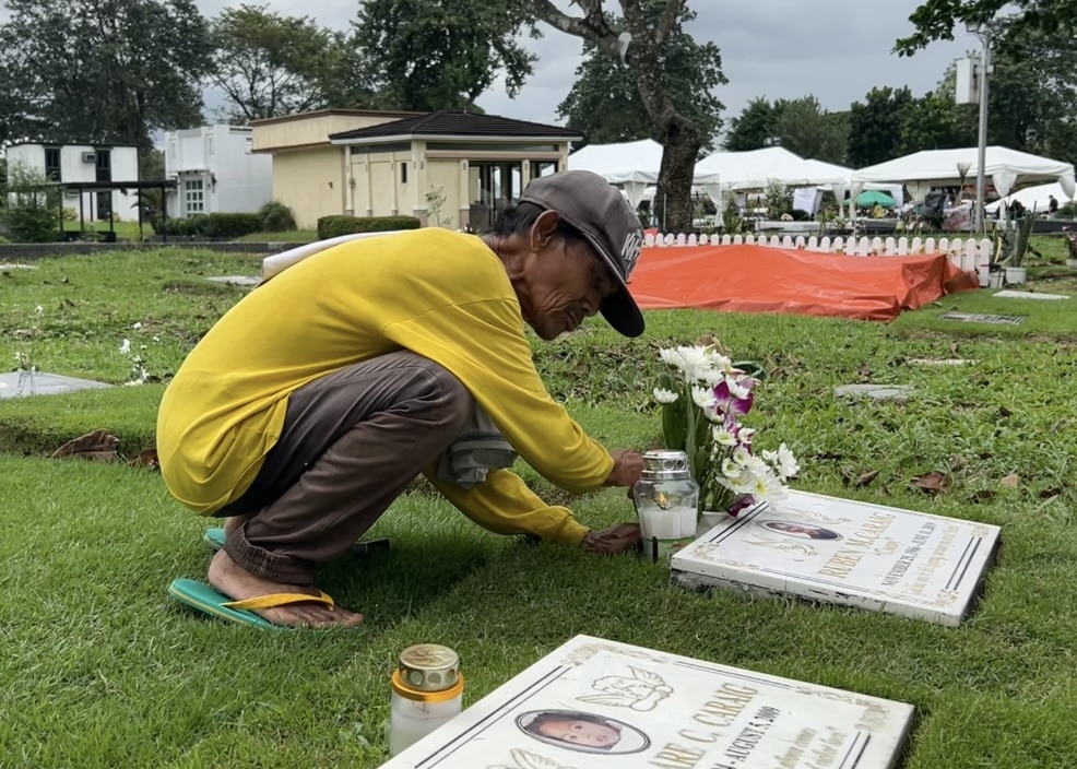 Danilo Bandojo, 65, cleans the lot of a tombstone under his care at the Loyola Memorial Park on Thursday, October 31.