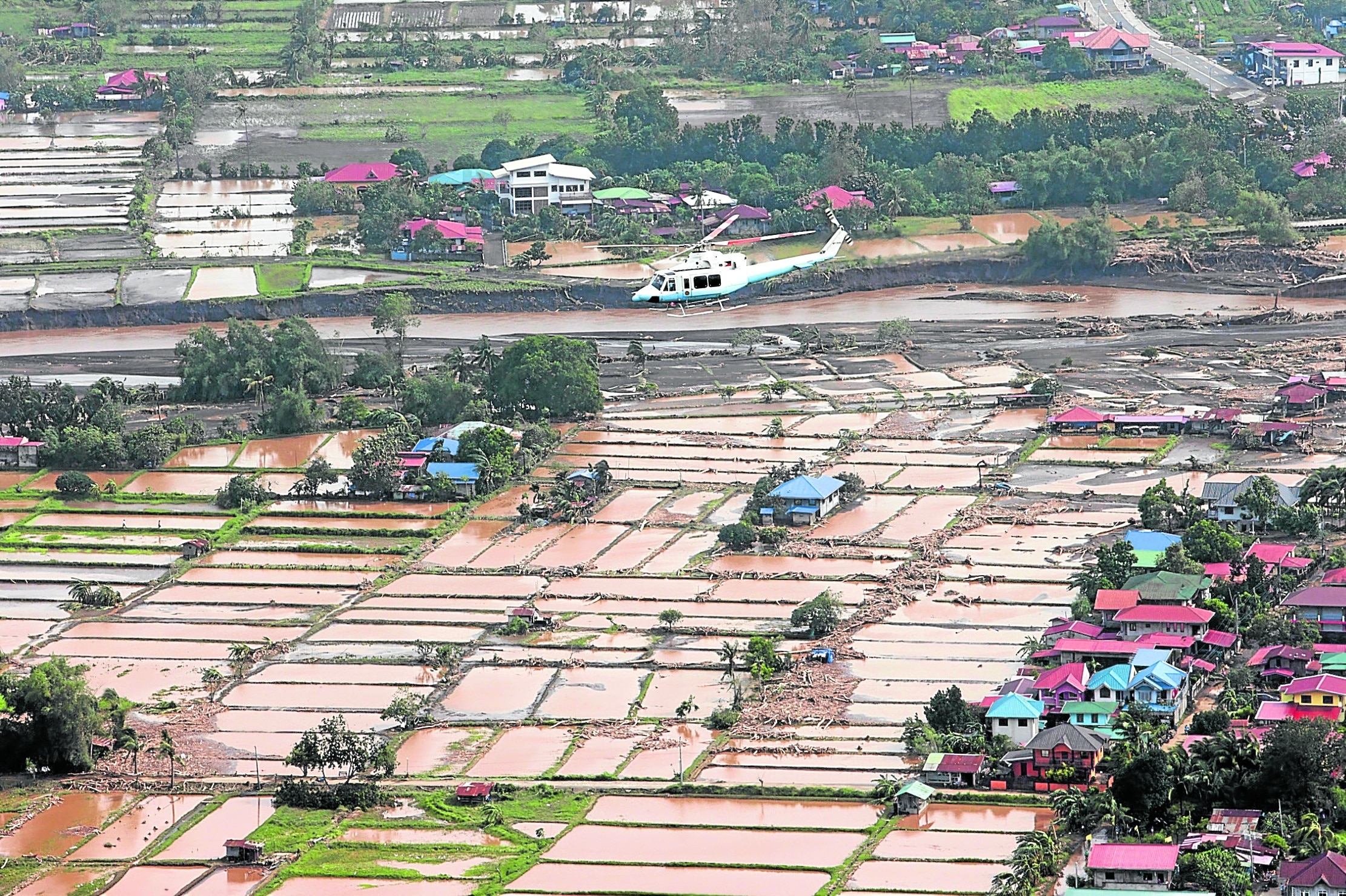 AERIAL INSPECTION Photo shows a helicopter carryingPresident Marcos over flooded rice fields in Batangas. 