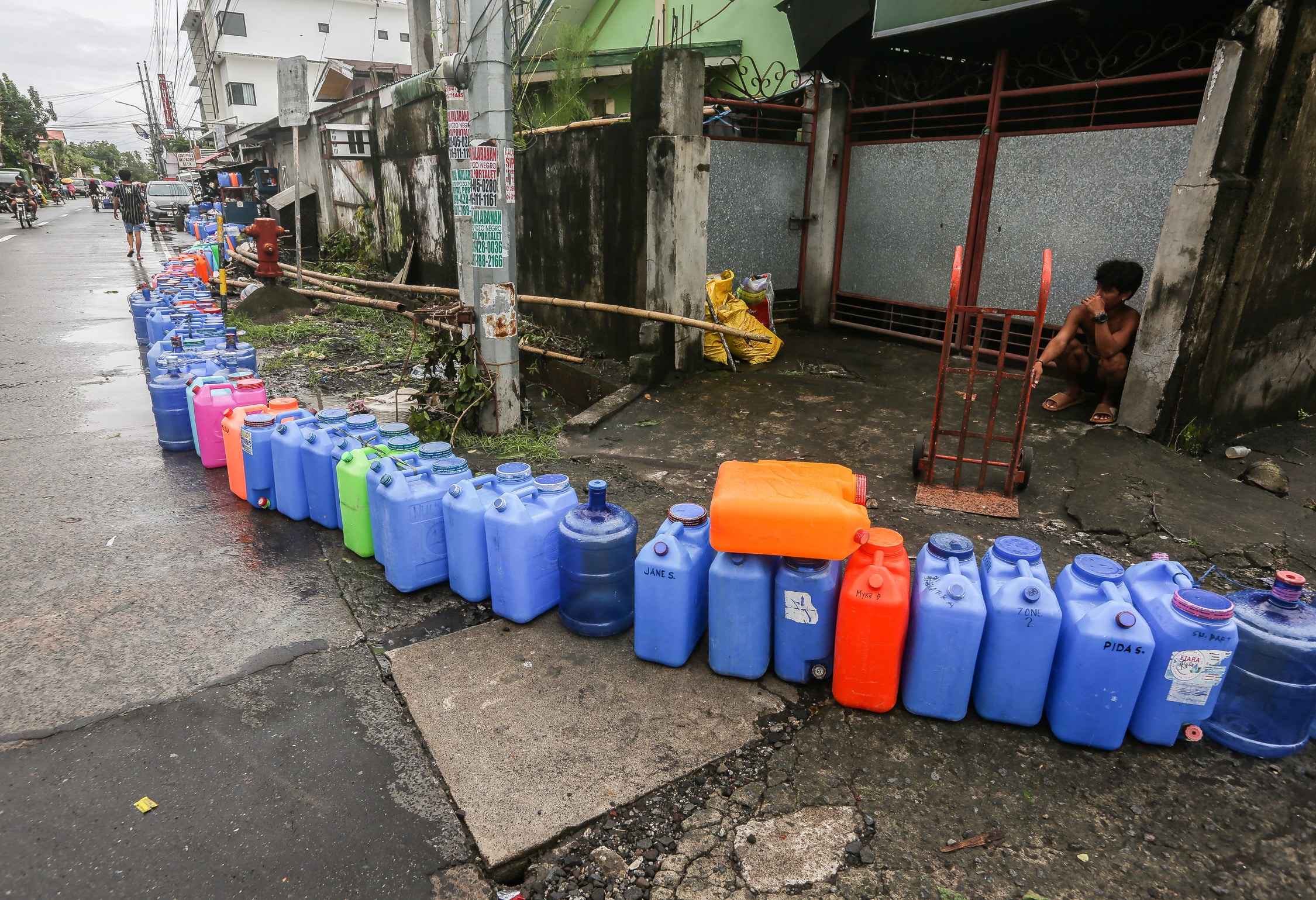 FIRST SIGNS OF SHORTAGE Containers form a long line leadingto a water station in Libon town, Albay province, on Thursday as the region reels from the devastation wrought by Severe Tropical Storm “Kristine.”