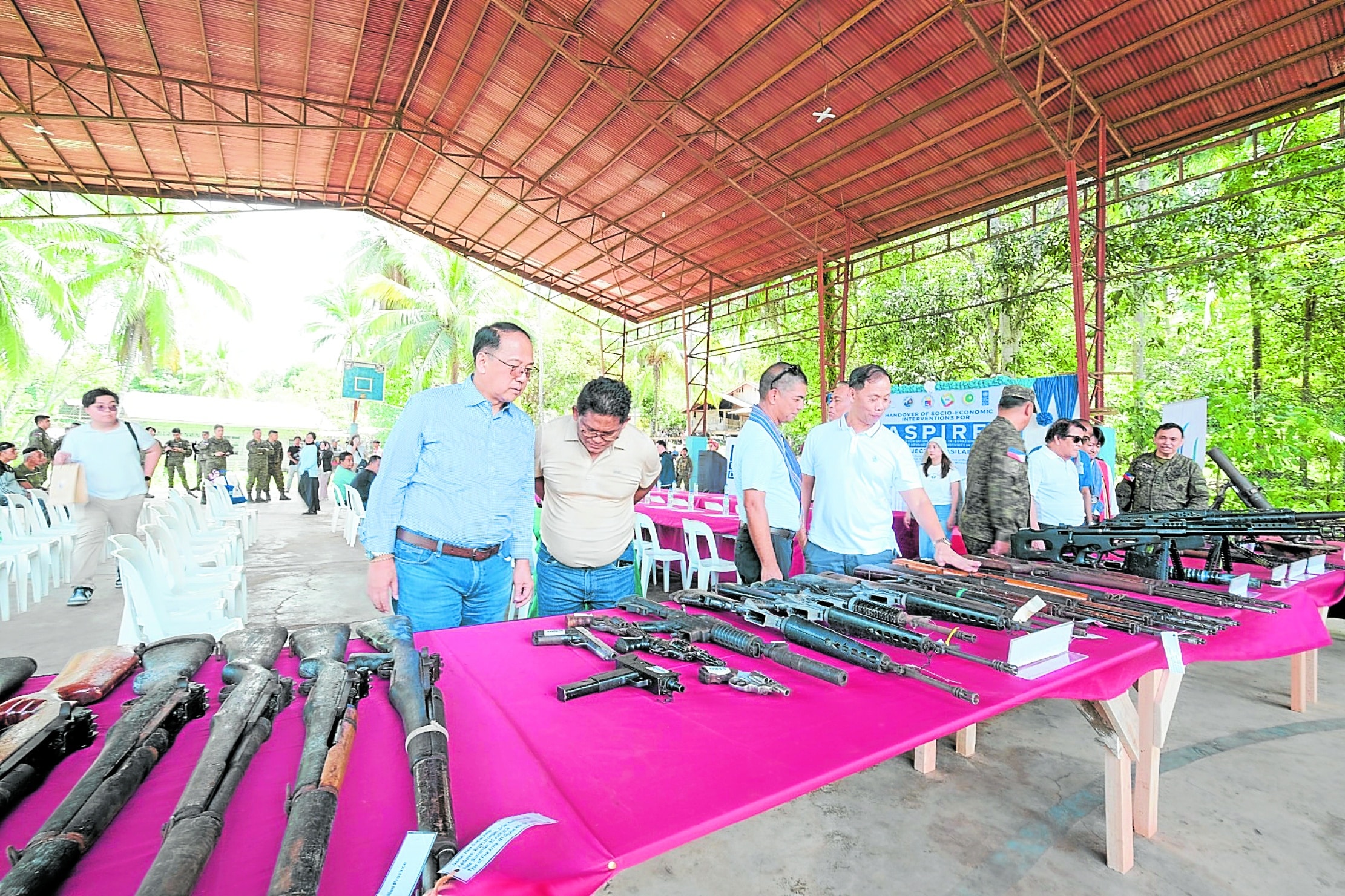 SURRENDERED Presidential Peace Adviser Carlito Galvez Jr.(first, left) examines the guns surrendered to authorities by residents
of Basilan on Oct. 17 as part of a government program to
siphon off loose firearms in the Bangsamoro region. 