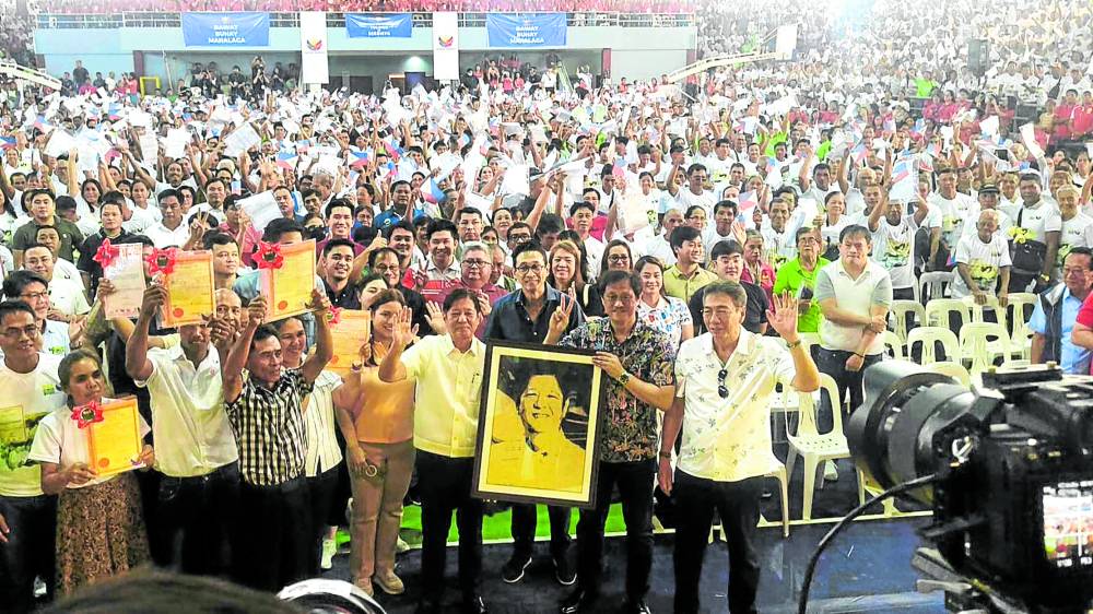 OWNERS AT LAST President Marcos, holding a portrait giftedto him, joins thousands of agrarian reform beneficiaries with their land certificates in a programin Cabagan, Isabela, on Friday. 