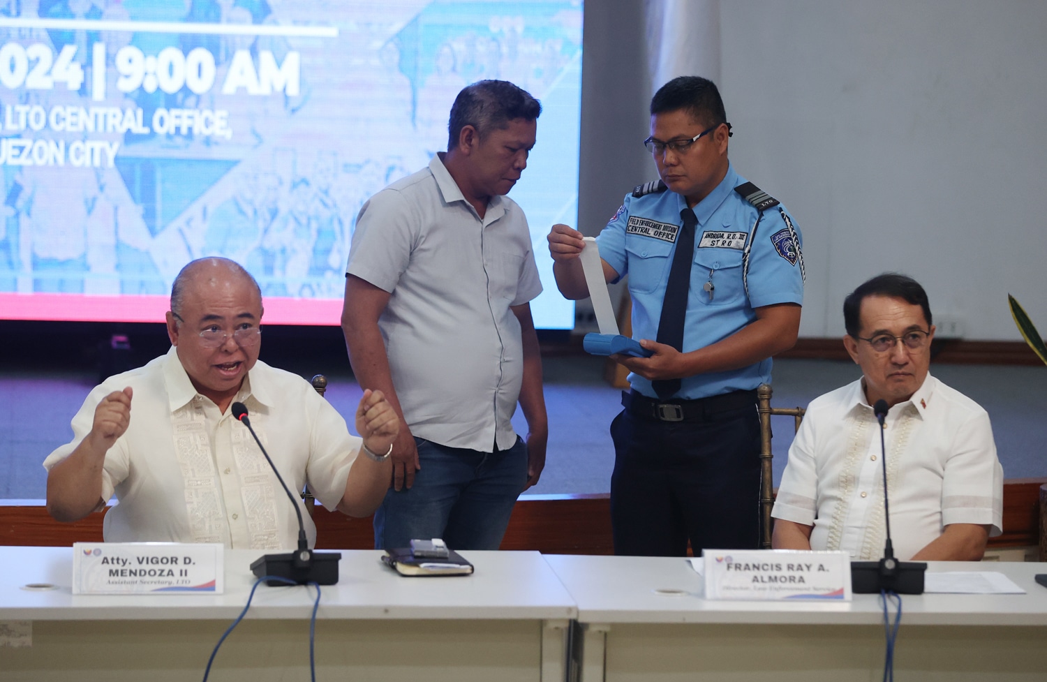 TICKETED, FINALLY Angelito Edpan (left, standing), thedriver of thewhite Cadillac Escalade with a “7” protocol plate that was caught in a viral video illegally using the Edsa bus lane over the weekend, is issued a traffic violation ticket by a Land Transportation Office (LTO) enforcer onWednesday. Edpan,who escaped apprehension by driving off, was presented in a press briefing held at LTOmain office inQuezon City by (fromleft, seated) LTOchief VigorMendoza ll and LTOLawEnforcement Service director Francis Ray Almora. 