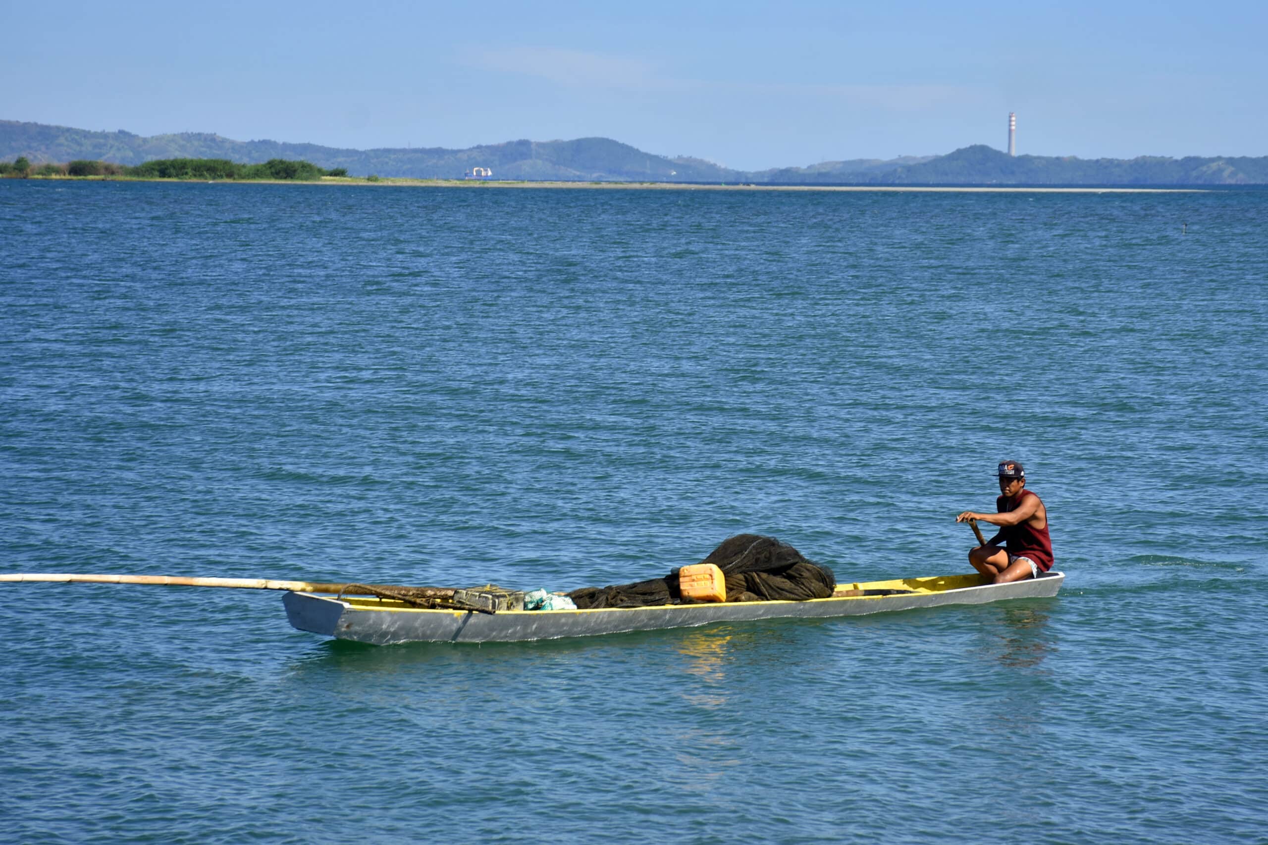 THROUGH THE CHANNEL A fishing boat coming from Lingayen Gulf enters the Limahong River Channel and Delta, in this photo taken in 2022. The chimney of Sual Power Plant is visible in the background. 