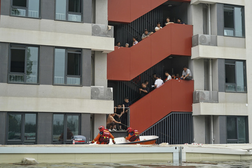 In this photo released by Xinhua News Agency, rescuers use boat to evacuate trapped residents at an apartment submerged by flood water in Fangshan district on the outskirts of Beijing on Wednesday, Aug. 2, 2023. China's capital has recorded its heaviest rainfall in at least 140 years over the past few days as remnants of Typhoon Doksuri deluged the region, turning streets into canals where emergency crews used rubber boats to rescue stranded residents. (Ren Chao/Xinhua via AP)