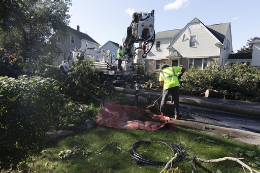 A utility crew works amongst fallen trees in a residential neighborhood, Friday, Aug. 18, 2023, in Johnston, R.I.